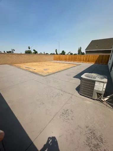 Large poured concrete patio slab filling a fenced back yard