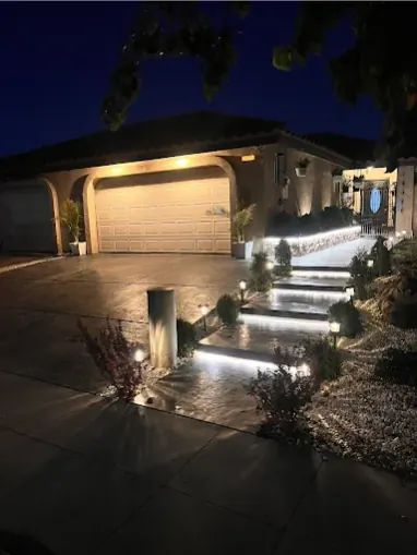 Floating concrete steps lit from beneath, leading up a stamped driveway at night